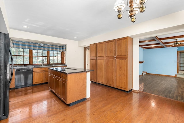 kitchen with hardwood / wood-style floors, dark stone counters, coffered ceiling, a center island, and black appliances