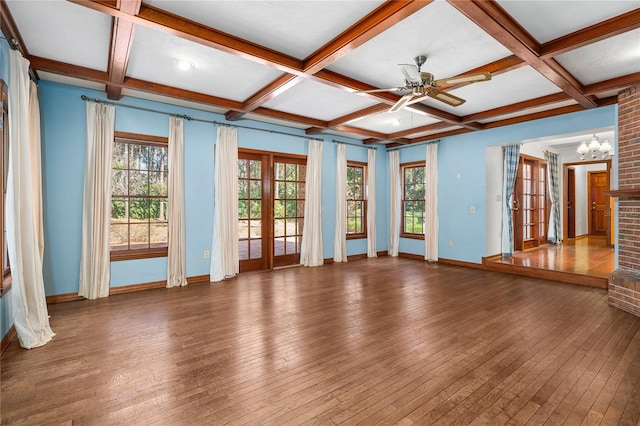 interior space with dark hardwood / wood-style flooring, ceiling fan with notable chandelier, and coffered ceiling