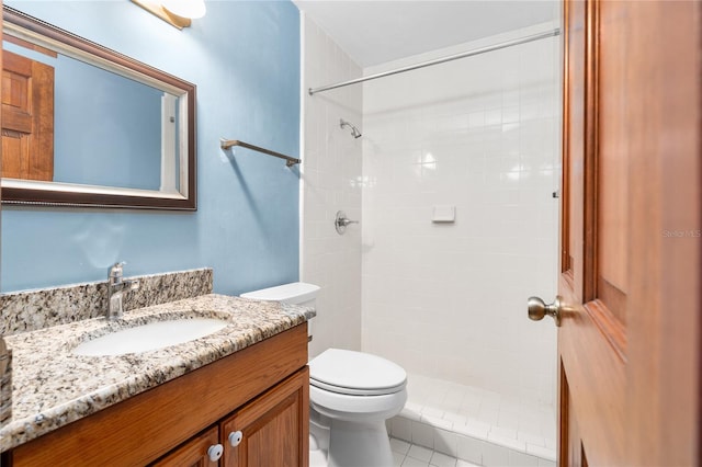 bathroom with tiled shower, vanity, and toilet