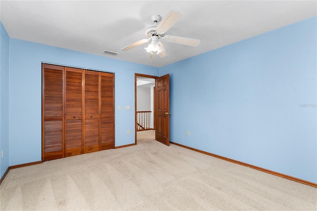 unfurnished bedroom with light carpet, a closet, and ceiling fan