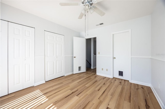 unfurnished bedroom featuring multiple closets, light wood-type flooring, and ceiling fan