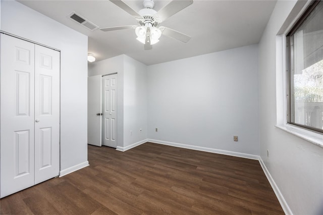 unfurnished bedroom with multiple closets, dark hardwood / wood-style flooring, and ceiling fan