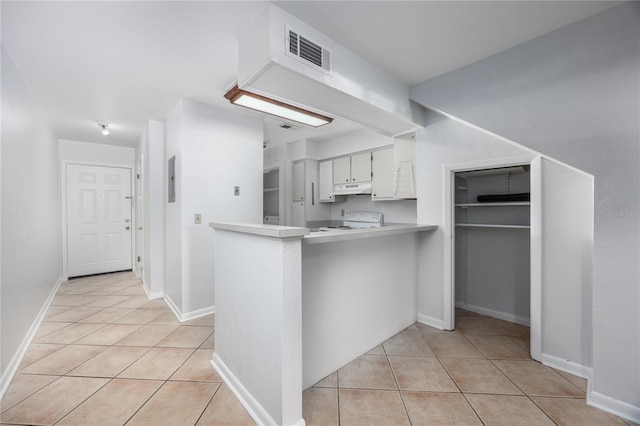 kitchen featuring electric stove, light tile patterned floors, white cabinets, and kitchen peninsula