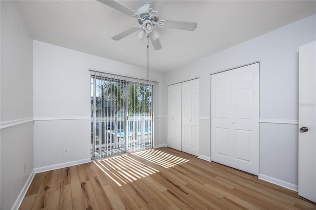 unfurnished bedroom with two closets, ceiling fan, and light wood-type flooring