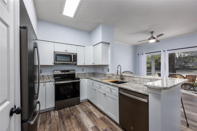 kitchen featuring a kitchen breakfast bar, kitchen peninsula, white cabinets, and appliances with stainless steel finishes