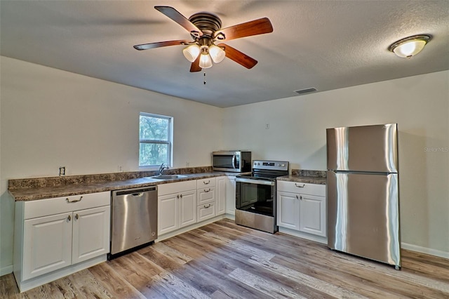 300 S US Highway 129, Bell, FL 32619 - kitchen featuring sink, white cabinetry, stainless steel appliances, a textured ceiling, and light wood-type flooring