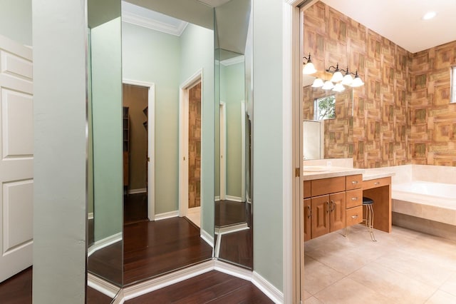 bathroom with crown molding, tile patterned floors, vanity, and tiled bath