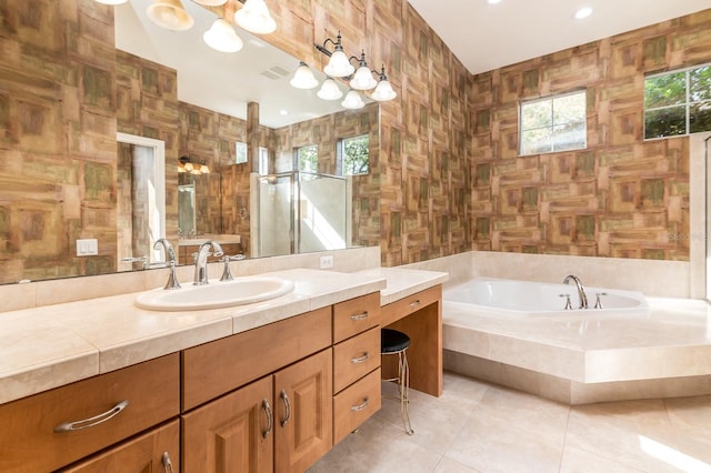 bathroom with tile patterned flooring, vanity, tiled tub, and tile walls