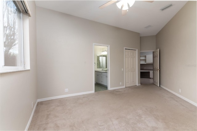 unfurnished bedroom with sink, ceiling fan, light carpet, ensuite bath, and a closet