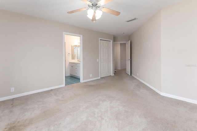 unfurnished bedroom featuring ceiling fan, light colored carpet, and connected bathroom