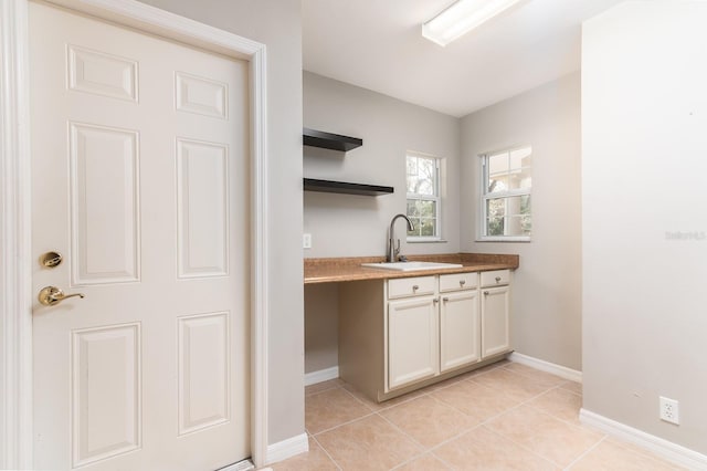 kitchen with white cabinetry, sink, and light tile patterned floors