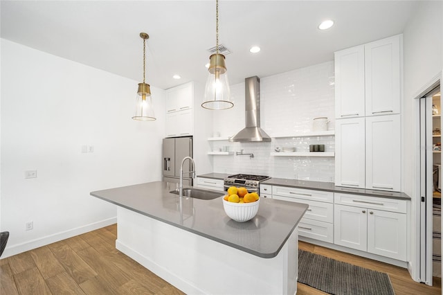 kitchen with decorative light fixtures, white cabinetry, sink, stainless steel appliances, and wall chimney exhaust hood