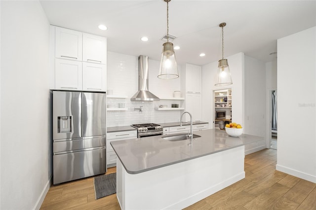 kitchen featuring pendant lighting, sink, white cabinets, stainless steel appliances, and wall chimney exhaust hood