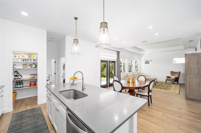 kitchen featuring sink, a center island with sink, dishwasher, pendant lighting, and white cabinets