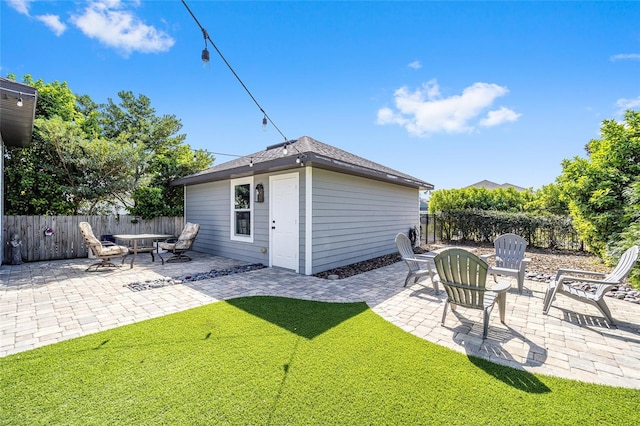 back of house featuring a patio and an outbuilding