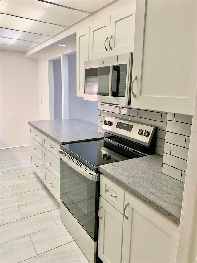 kitchen featuring white cabinetry, light stone counters, tasteful backsplash, and stainless steel appliances