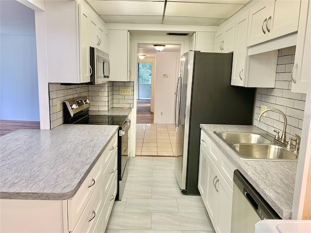 kitchen with appliances with stainless steel finishes, sink, light tile patterned floors, and white cabinets