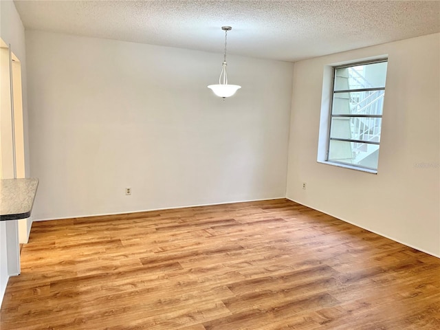 unfurnished dining area with light hardwood / wood-style flooring and a textured ceiling