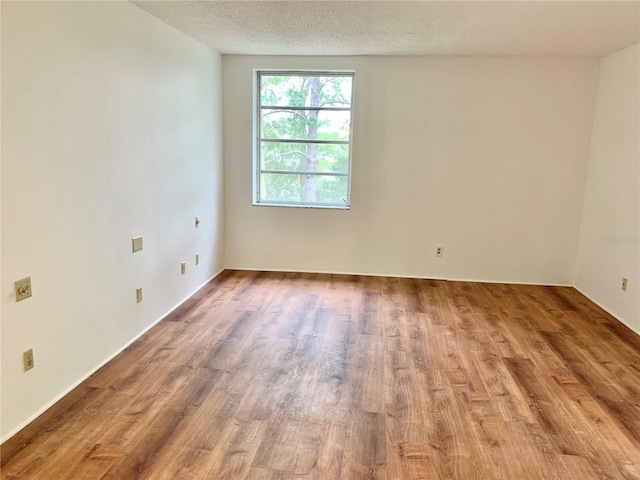 empty room with hardwood / wood-style flooring and a textured ceiling