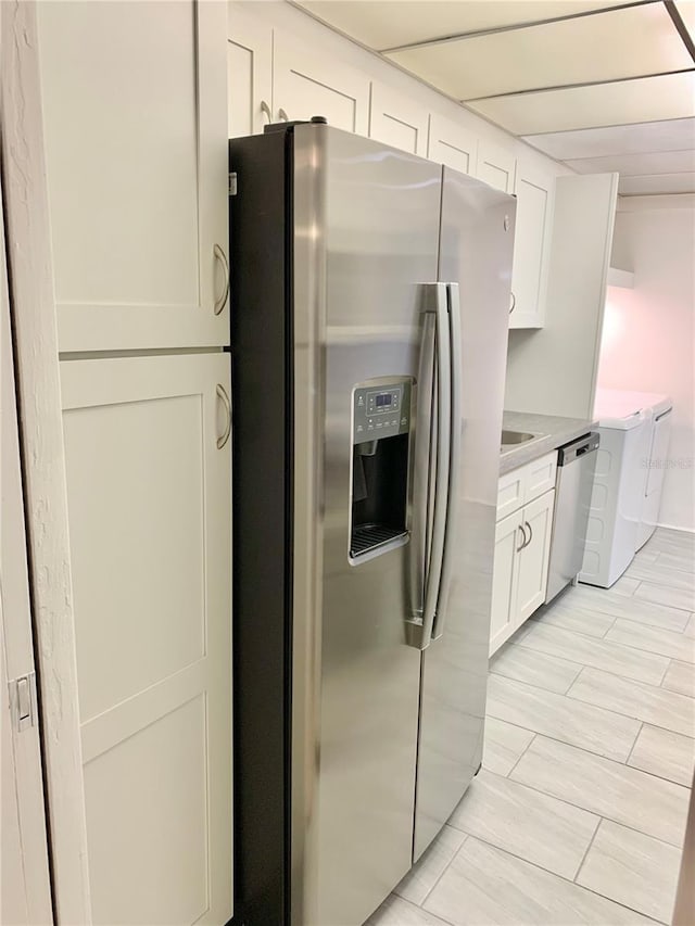 kitchen featuring washer / clothes dryer, stainless steel appliances, and white cabinets