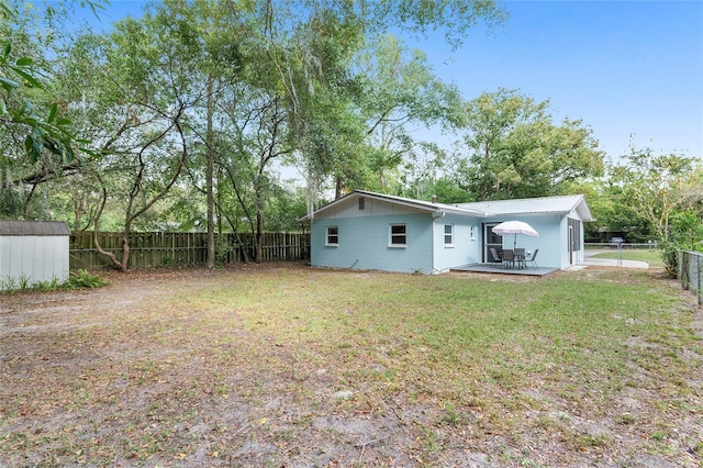 rear view of house featuring a yard, a patio area, and a storage shed