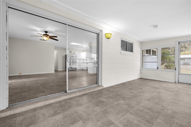 unfurnished sunroom featuring ceiling fan