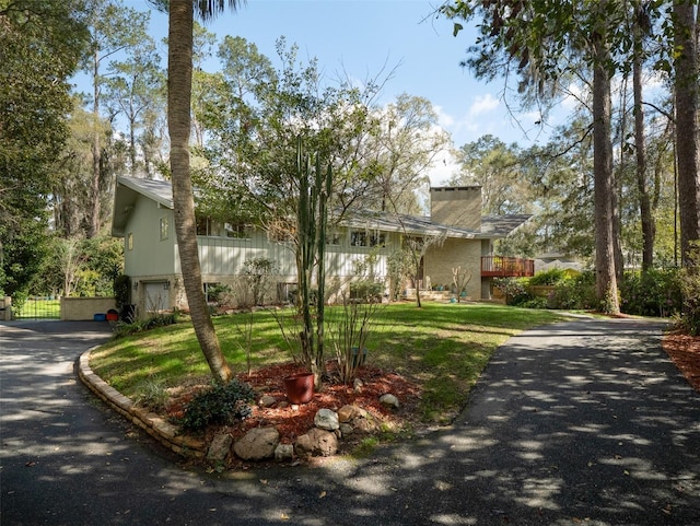 view of front of property featuring aphalt driveway, a front lawn, and a garage