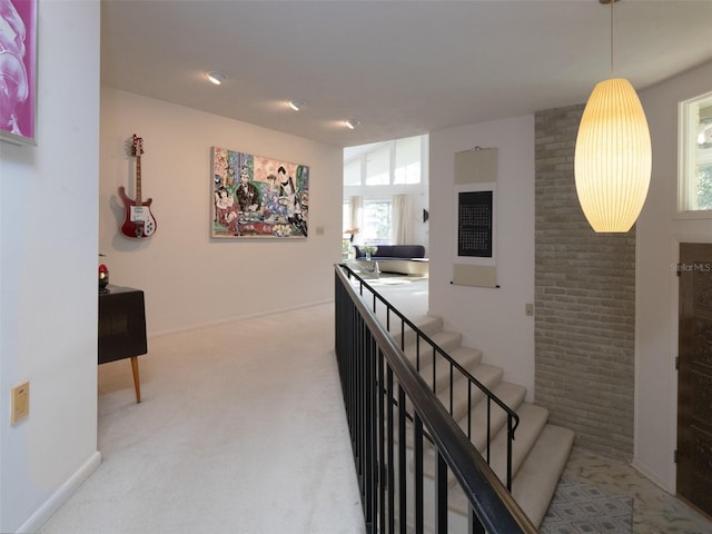 hallway featuring baseboards, stairway, and light colored carpet