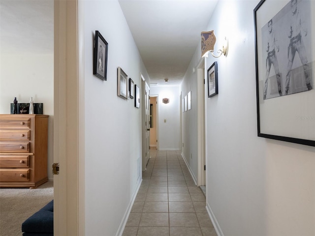 hall featuring light tile patterned floors and baseboards