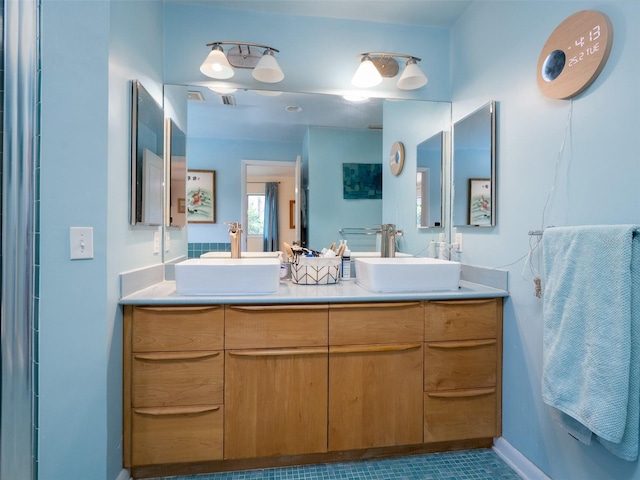 full bathroom with double vanity, baseboards, and a sink