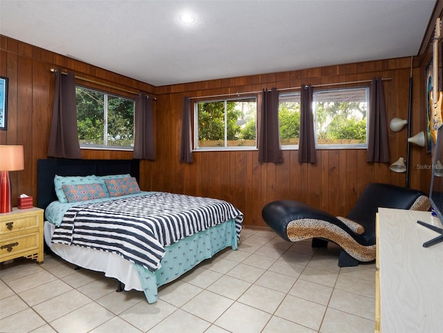 bedroom featuring wooden walls, multiple windows, and light tile patterned flooring