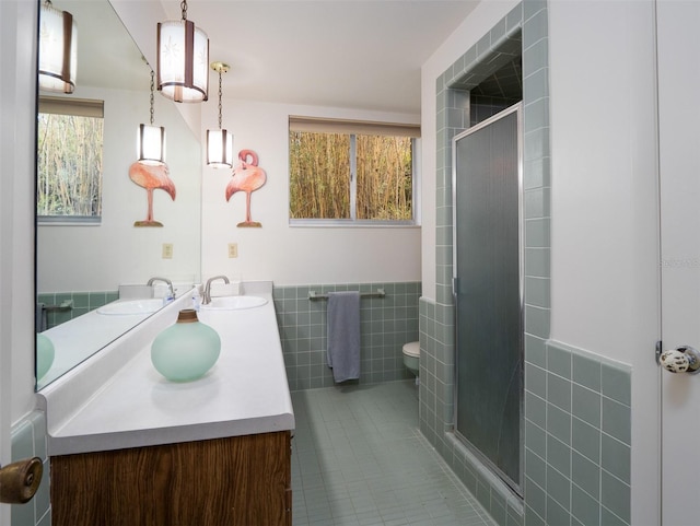 full bathroom featuring toilet, a stall shower, a sink, and tile walls