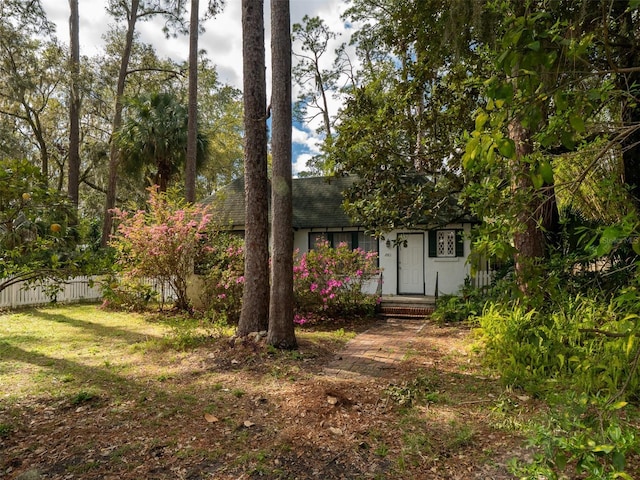 view of front facade featuring a front lawn, roof with shingles, and fence