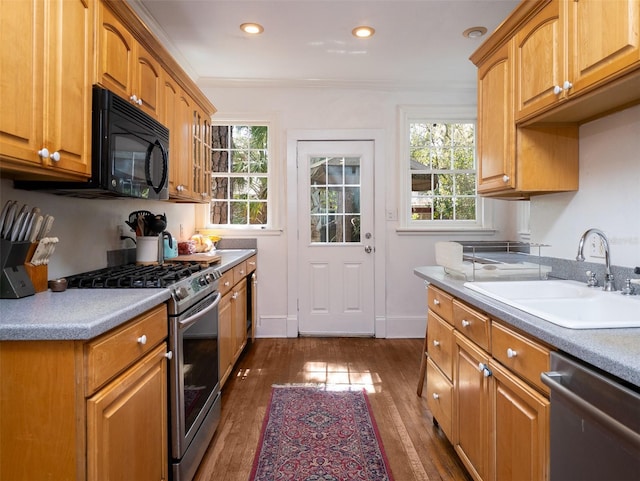 kitchen with dark wood-style floors, appliances with stainless steel finishes, a sink, and crown molding