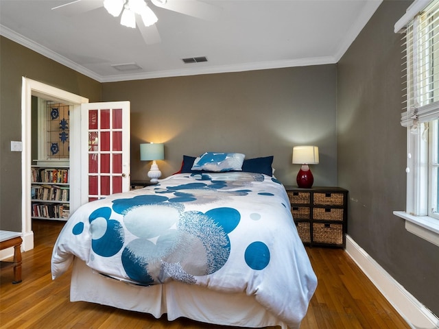 bedroom featuring visible vents, crown molding, baseboards, and wood finished floors