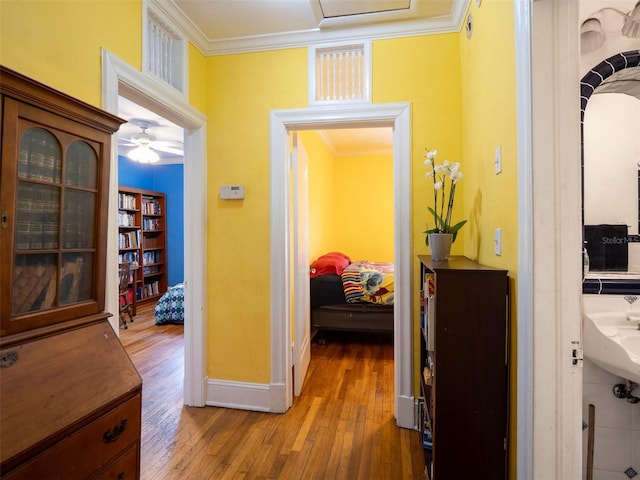 hall with wood-type flooring, ornamental molding, and baseboards