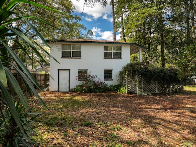 rear view of house with fence and stucco siding