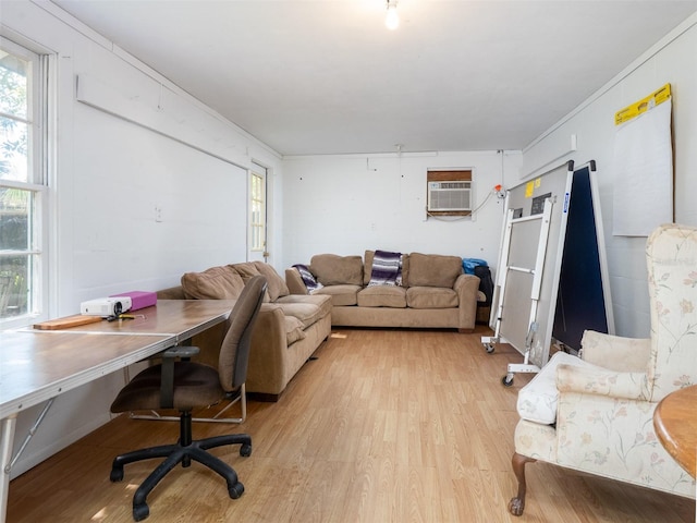 living room with ornamental molding, a wall mounted air conditioner, and light wood-style flooring