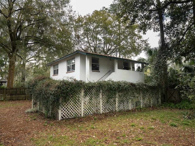 view of side of home with fence and stucco siding