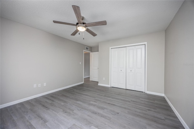 unfurnished bedroom featuring ceiling fan, hardwood / wood-style floors, a closet, and a textured ceiling