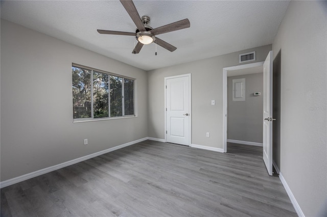 unfurnished bedroom with hardwood / wood-style flooring, ceiling fan, and a textured ceiling