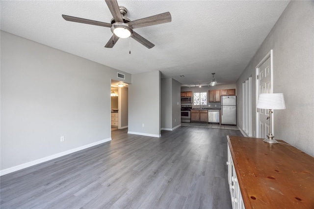 unfurnished living room with ceiling fan, dark hardwood / wood-style floors, and a textured ceiling