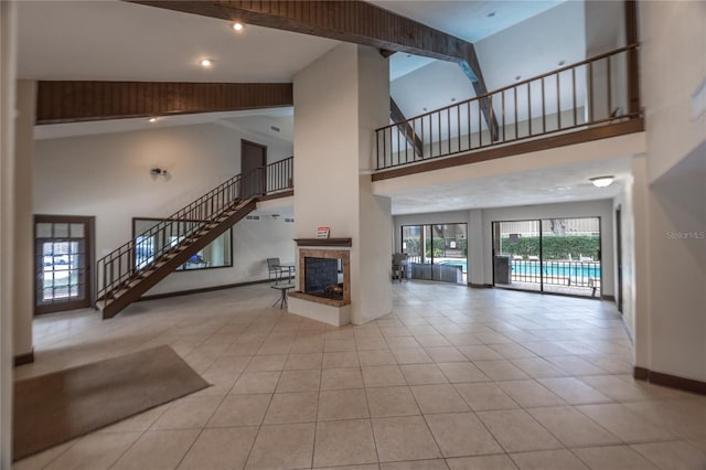 interior space with a high ceiling, a multi sided fireplace, and light tile patterned floors