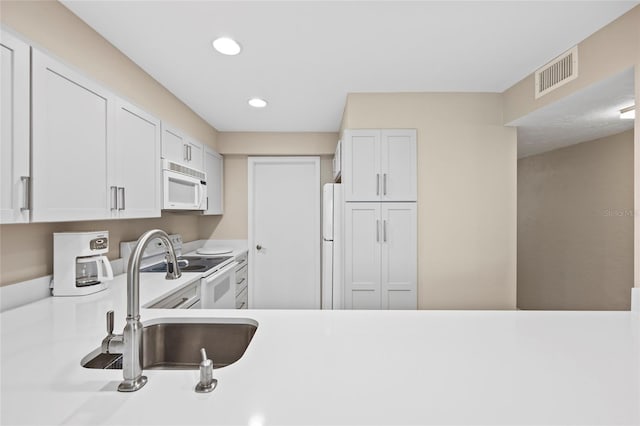 kitchen with white cabinetry, sink, and white appliances