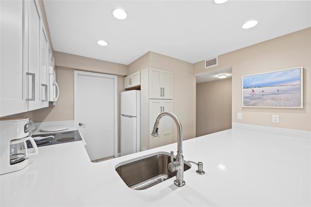 kitchen with sink, white appliances, and white cabinets