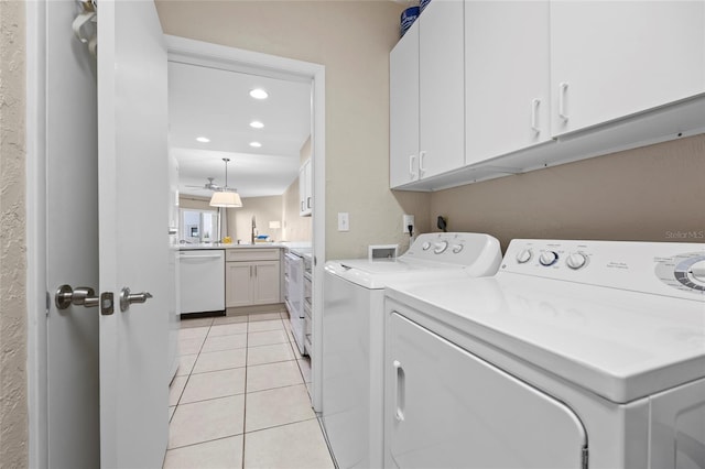 laundry room featuring cabinets, sink, light tile patterned floors, and washing machine and clothes dryer