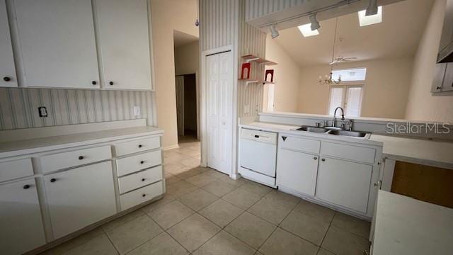 kitchen with lofted ceiling, sink, dishwasher, white cabinetry, and hanging light fixtures