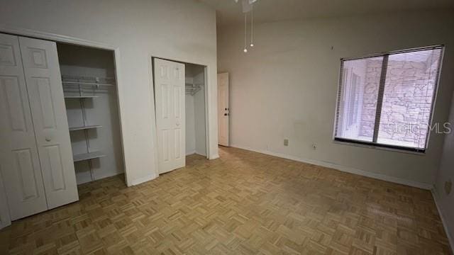 unfurnished bedroom featuring parquet floors and multiple closets