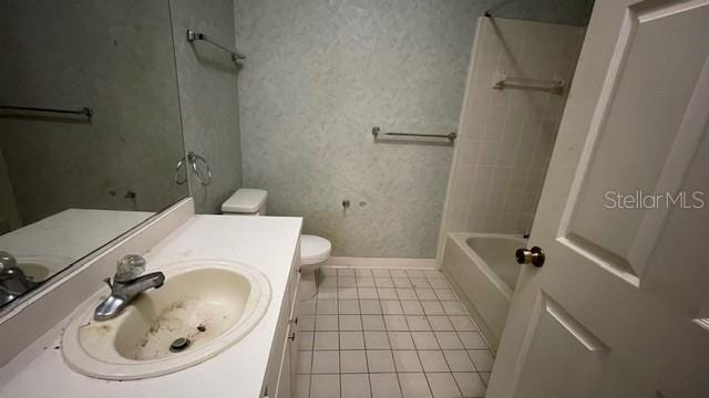 full bathroom featuring tile patterned flooring, vanity, tiled shower / bath, and toilet