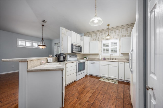 kitchen featuring white appliances, kitchen peninsula, hanging light fixtures, and white cabinets